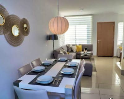 una cocina con mesa y lámpara, zona de estar, armarios brillantes